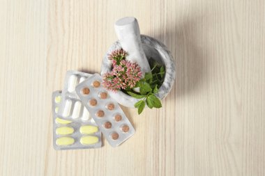 Havan mermisi taze bitkiler ve haplar ahşap masada, düz yatıyordu.