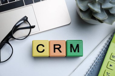Aydınlık ofis masasında dizüstü bilgisayarı olan küplerin kısaltması CRM. Müşteri İlişkileri Yönetimi