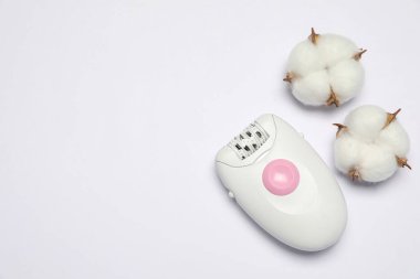 Beyaz arka planda modern epilator ve pofuduk pamuk çiçekleri, üst görünüm
