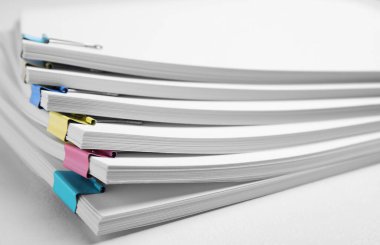 Many sheets of paper with colorful clips on white background, closeup