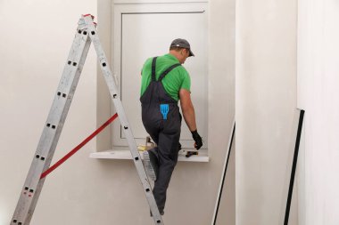 Üniformalı işçiler çift camlı pencereler kuruyor.
