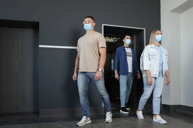 Asansörden çıkan maskeli bir grup insan. Koruyucu önlem