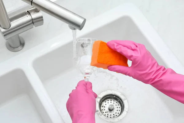 Woman washing glass with sponge in kitchen sink, above view