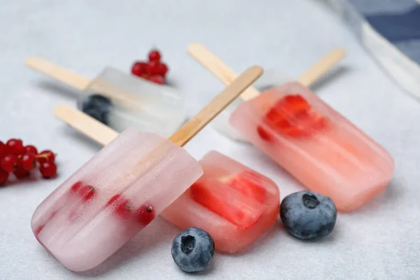 Tasty berry ice pops on light table, closeup