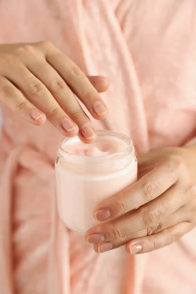 Woman holding jar of hand cream, closeup