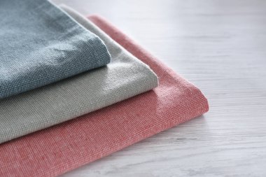 Beyaz ahşap masada farklı renkli peçeteler, yakın plan. Metin için boşluk