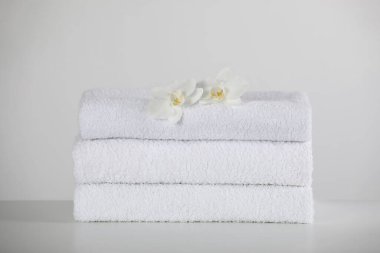 Beyaz masa üzerinde yumuşak katlanmış havlular ve orkide çiçekleri