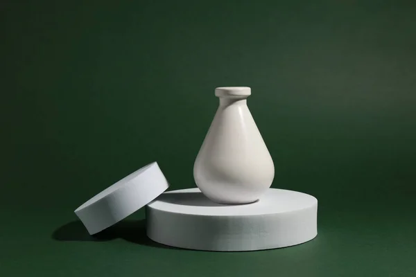 Product photography props. Round shaped podiums and vase on green background