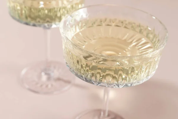 Glasses of expensive white wine on pink background, closeup