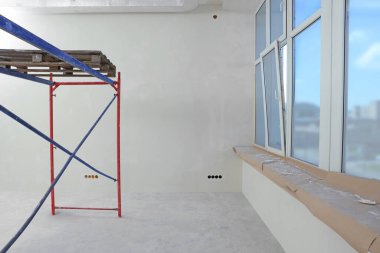 Boş odadaki iskele tadilat için hazırlanıyor.