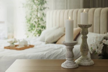Yatak odasındaki ahşap masada bir çift güzel şamdan.