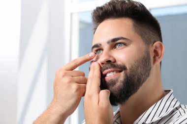 Genç adam içeride kontak lens takıyor.