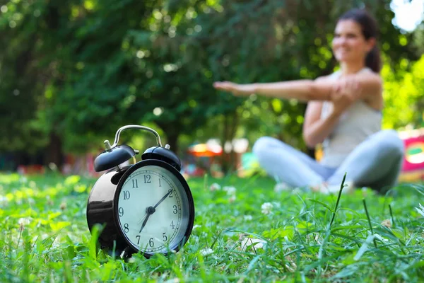 公園で朝の運動をしている若い女性目覚まし時計に焦点を当て — ストック写真