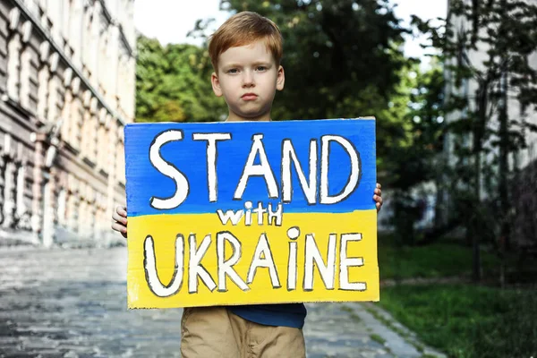 悲しい男の子は国旗と言葉の色でポスターを保持市内通りにウクライナと一緒に立つ — ストック写真