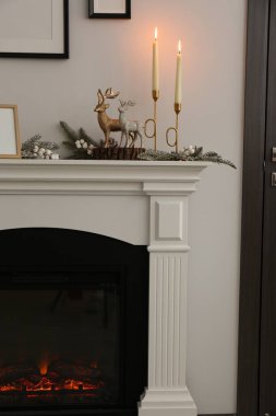 Beyaz duvarın yanındaki şöminenin iç dekorasyonları çok şık.