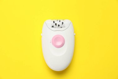 Sarı arkaplanda modern epilatör, üst görünüm