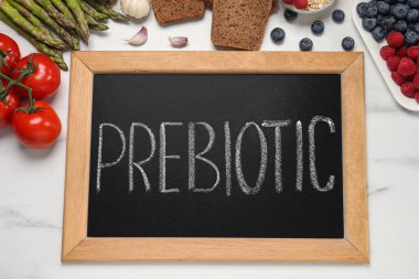 Tahtada prebiyotik ve beyaz mermer masa üzerinde farklı ürünler var.