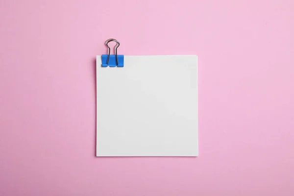 Sheet of paper with clip on pink background, top view