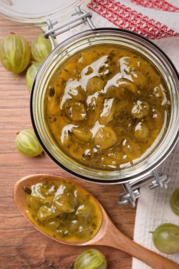 Kavanoz, lezzetli bektaşi üzümü reçelli kaşık ve ahşap masada taze böğürtlen.