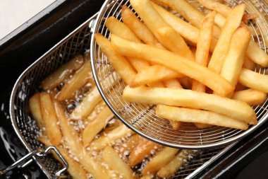 Delicious freshly prepared french fries in metal strainer, closeup