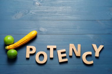 Kelimenin gücü harflerden, kabaktan ve limonlardan oluşuyor. Mavi ahşap masadaki erkek üreme organlarını sembolize ediyor. Metin için yeri olan düz bir yer.