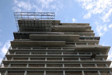 Multistory building under construction against cloudy sky, low angle view