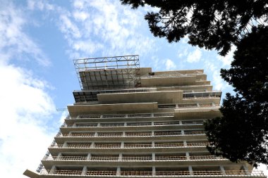 Multistory building under construction against cloudy sky, low angle view