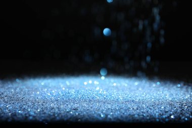 Siyah arkaplana dökülen parlak mavi parıltı. Bokeh etkisi