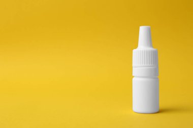 Sarı arka planda bir şişe tıbbi damla. Metin için boşluk