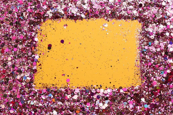 Frame of shiny bright pink glitter on yellow background, flat lay. Space for text