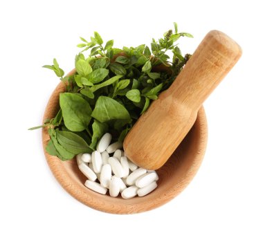 Taze yeşil otlu havan ve beyaz arka planda haplar.