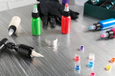 Modern profesyonel dövme makinesi, renkli mürekkep ve merhem salonda masanın üstünde.