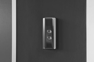 Gri duvardaki asansör çağrı düğmeleri, yakın plan.