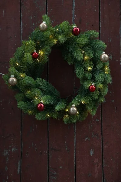 Piękny Świąteczny Wieniec Bombkami Lampkami Wiszącymi Brązowej Drewnianej Ścianie — Zdjęcie stockowe