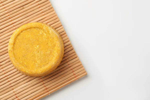 Yellow solid shampoo bar on light table, top view. Space for text