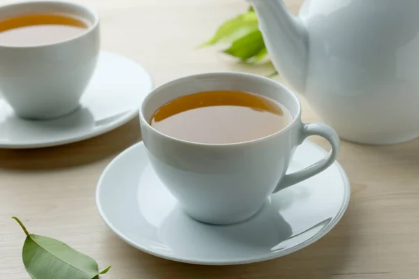 木製のテーブルの上に葉やティーポットと白いカップで緑茶 クローズアップ — ストック写真