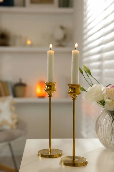 部屋の白いテーブルの上に美しい黄金の燭台のペア — ストック写真