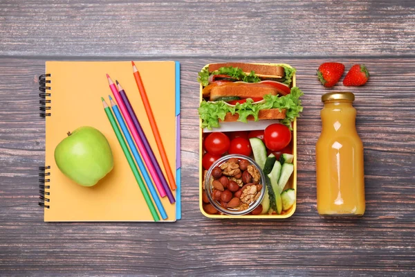 带健康食品的午餐盒 学生用 木制桌子上有不同的文具 — 图库照片