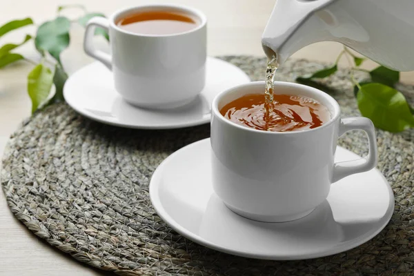 テーブルの上にソーサー付きの白いカップに緑茶を入れ 閉じます — ストック写真