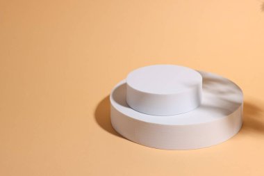 Soluk turuncu arkaplan üzerinde ürün sunumu için podyum olarak yuvarlak şekiller, metin için boşluk