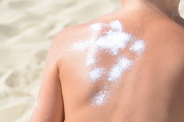 Sahilde güneş kremi sürmüş bir çocuk, yakın plan.