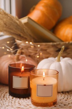 İçerideki hasır paspasın üzerinde kokulu mumlar ve balkabakları