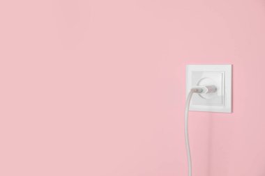 Pembe duvardaki güç prizine bağlı şarj adaptörü, mesaj için boşluk. Elektrik arzı