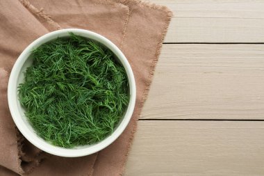 Tahta masanın üstünde bir kase taze dereotu, üst manzara. Metin için boşluk