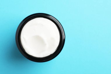 Açık mavi arka planda bir kavanoz yüz kremi, üst manzara. Metin için boşluk