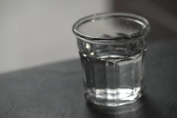 Glas Zuiver Water Zwarte Tafel Tegen Wazige Achtergrond Ruimte Voor — Stockfoto