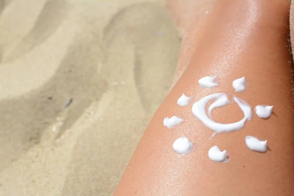 Sun drawn with sunscreen on woman\'s leg at beach, closeup. Space for text