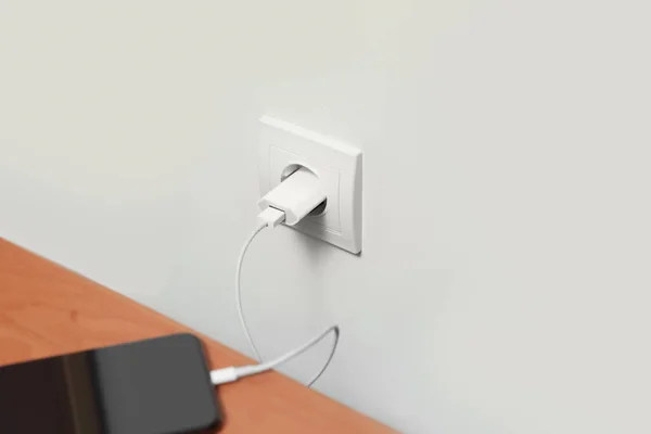 Modern smartphone charging from electric socket indoors