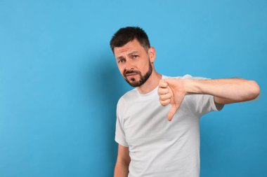Açık mavi arkaplanda baş parmağını gösteren adam, metin için boşluk