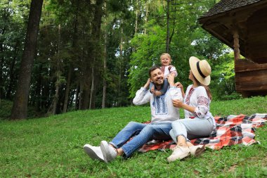 Happy family in Ukrainian national clothes on green grass outdoors